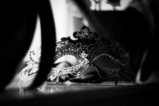 A black and white portrait of a venetian mask lying on a marble windowsill ready to put on and go to a masked ball, carnaval or halloween party.