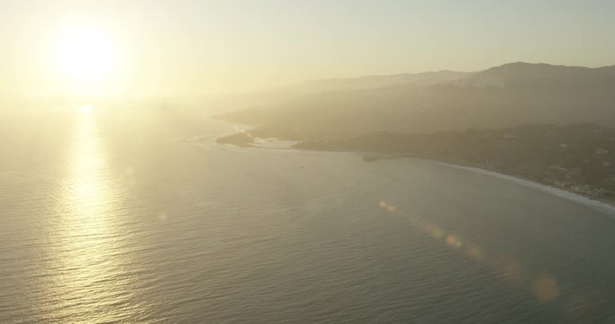 Helicopter aerial shot of sunsetting by cliffside ocean view