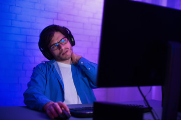Tired gamer playing video games, suffering from neck pain