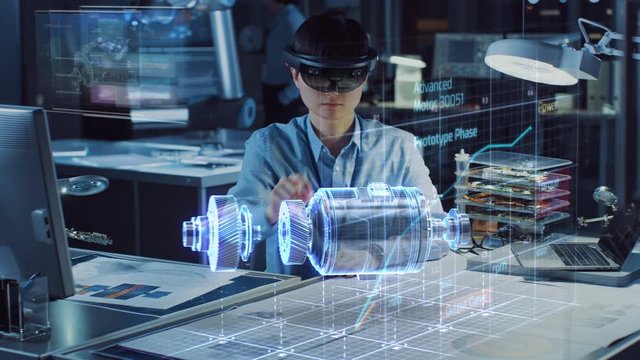 Industrial Factory Chief Engineer Wearing AR Headset Designs a Prototype of an Electric Motor on the Holographic Smart Blueprint. Futuristic Virtual Design of Mixed Technology Application.