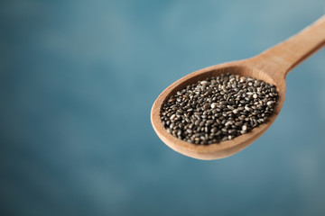 Chia seeds and spoon against blue background, close up