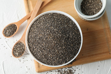 Bowl and spoons with chia on white background, top view