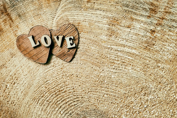 Word love from wooden letters on two wooden hearts, on wooden surface of saw cut, grunge texture , background