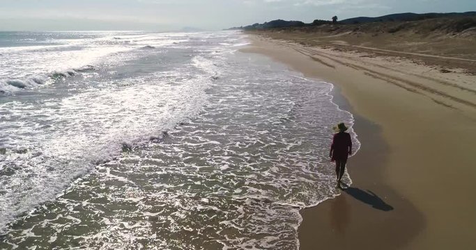 Bella mujer con pamela caminando solitaria por playa del mediterr&aacute;neo con arenas doradas