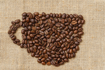 Coffee beans in the shape of a coffee cup on natural canvas, sackcloth