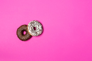 Different tasty donuts with chocolate icing on color background. View from above