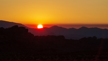 Orange and red sunrise wuth mountains silhuettes in the desert at Valley of Fire State Park, Nevada