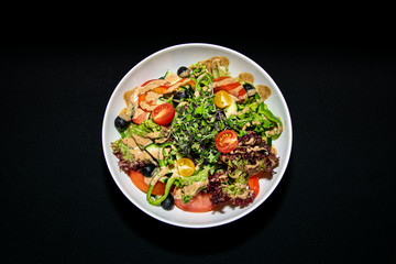 a traditional mixed green salad with mixed leaves, sliced peppers and cherry tomatoes 