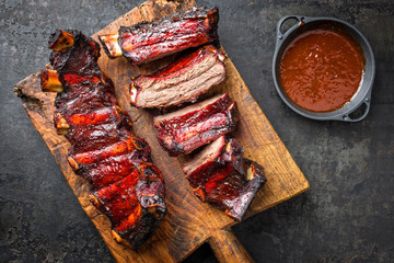 Barbecue chuck beef ribs with hot marinade and chili sauce as top on a wooden cutting board with...