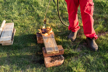 A man burns wooden planks with propane using old-time Japanese technology, creating facing material...