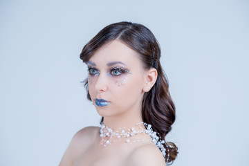 Portrait of a beautiful attractive girl with fantasy make up and hair style isolated on white background, series of photos.blue lips, elegant necklace, design hair. Conceptual art. Snow Queen.