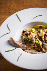 Veal tongues with stewed vegetables and cream sauce, garnished with rosemary