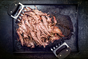Traditional barbecue wagyu pulled beef offered as top view on a rustic board in a metal tray