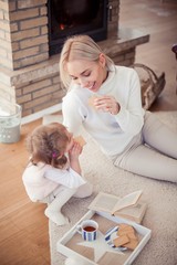 Beautiful young family is reading a book near the fireplace. Cozy.