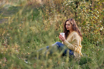 Fototapeta na wymiar woman sitting in autumn park with a cup of coffee