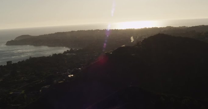 Helicopter aerial shot of mountainous coastline and highway, sundown