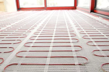 Elektrische Fußbodenheizung rote Matten auf Zementboden. Heizung rotes elektrisches Kabel auf Zementboden Kopie Raum Hintergrund. Renovierung und Bau, komfortables warmes Wohnkonzept. © Anna Ria