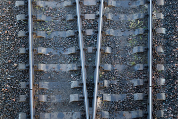 Two pairs of rails with sleepers of railway tracks diverge in different directions, with traces of grease on a background of rubble. Concept: Choosing the best solution or path out of the two proposed