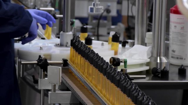worker on conveyor filling bottles of e-liquid