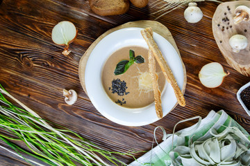 Mushroom soup with pasta with champignons and herbs on a brown wooden background
