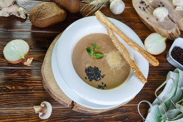 Mushroom soup with pasta with champignons and herbs on a brown wooden background