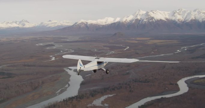 Helicopter aerial shot of biplane flying over majestic Alaskan landscape, drone