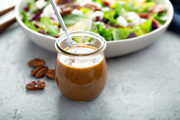 Balsamic vinaigrette dressing for a salad, small glass jar with a whisk
