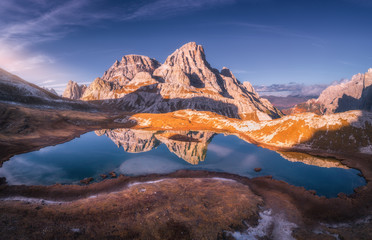 Aerial view of mountain lake with reflection at sunset in autumn. Landscape with purple sky, mountains, hills with grass, blue water in fall. Top view of high rocks. Beautiful nature. Dolomites, Italy - obrazy, fototapety, plakaty