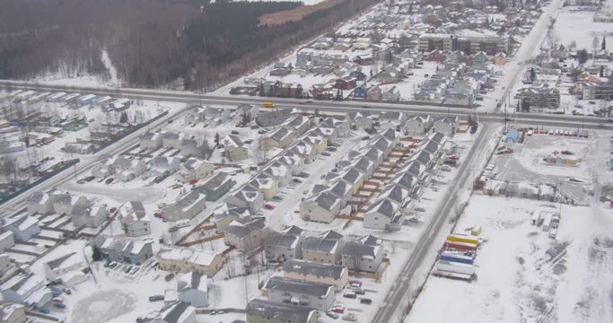 Aerial helicopter shot, overhead wide on suburban town during snowstorm, roads, businesses, drone footage