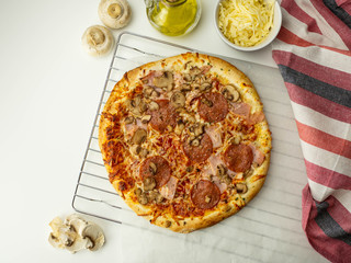 Pizza zrobiona w domu, salami, ser, pieczarki. Widok z góry.