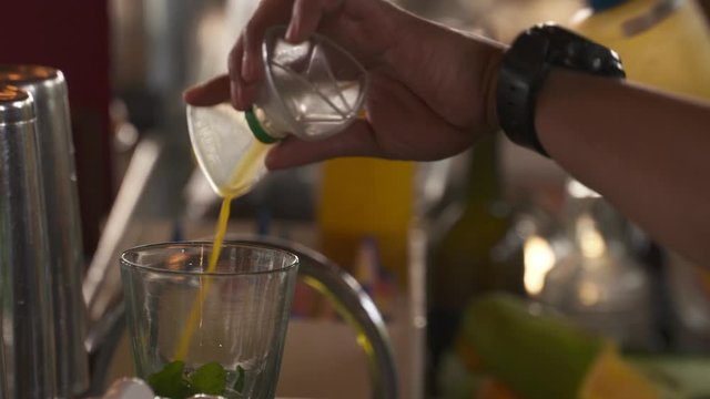 Close up of a bartender pouring ingredients into a glass to make a drink