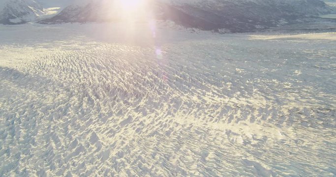  Aerial helicopter shot, details of rippling glacier at golden hour, lens flare, drone footage