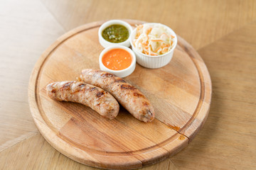 Grilled sausages. Serving on a wooden Board. Barbecue restaurant menu, a series of photos of different meats. Pickled cabbage and two sauces