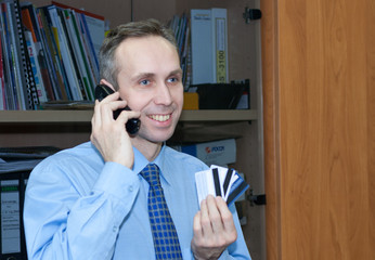 cheerful Manager holds several credit cards and talks on the phone