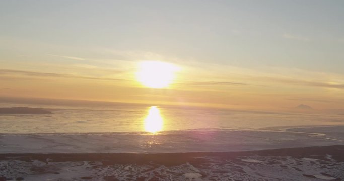  Aerial helicopter shot, tracking across a vast, icy Alaskan sea at golden hour, drone footage, sunset, lens flare