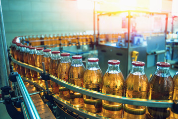 Conveyor belt, juice in bottles on beverage plant or factory interior in blue color, industrial...