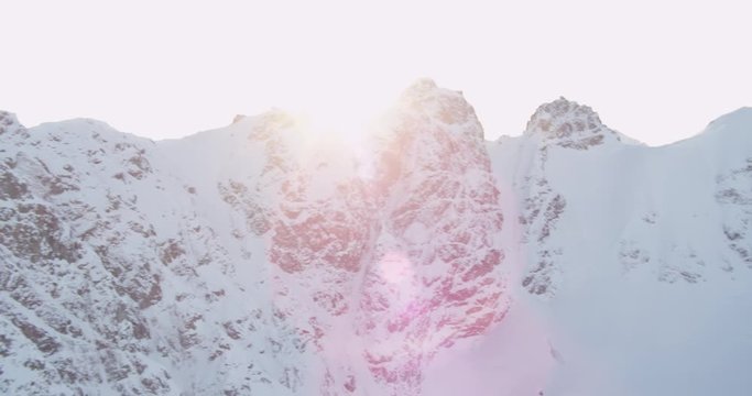  Aerial helicopter shot, panning back and forth over a rocky, snowy mountain at golden hour, lens flare, drone footage