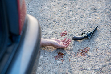 gun and hand at murder scene