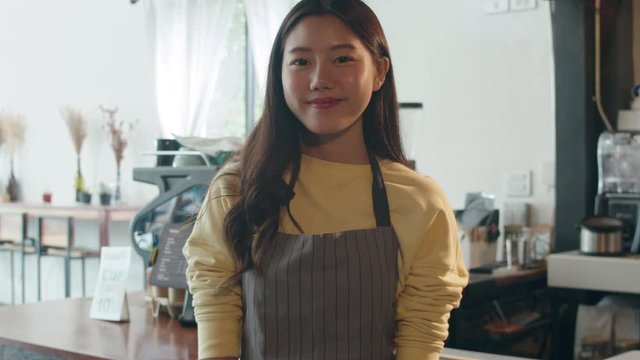 Portrait young Asian woman barista feeling happy smiling at urban cafe. Small business owner Korean girl in apron relax toothy smile looking to camera standing at the counter in coffee shop.