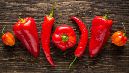 Assortment of fresh peppers on a textured dark wood background