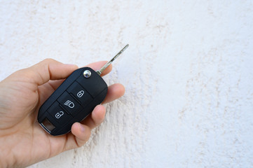 car key with remote control in female hand on white textured background