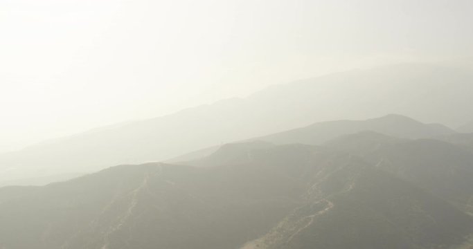 Aerial shot, day, hazy view of top of mountain range, drone