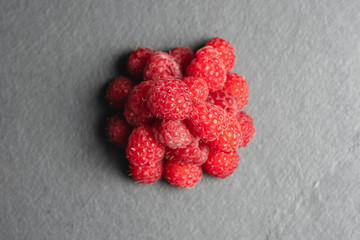 A handful of raspberries on a slate Board top view, close-up. Flat lay.
