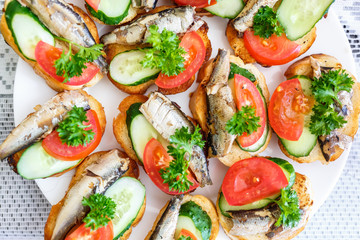 plate of sandwiches from long loaf, sprats, tomatoes, cucumbers and parsley