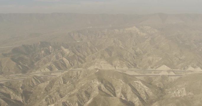 Aerial shot, day, hazy view of desert mountain range and highways, drone