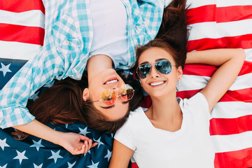Two attractive young girls relax on the us flag outdoors. Independence day