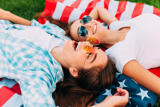 Two attractive young girls relax on the us flag outdoors. Independence day