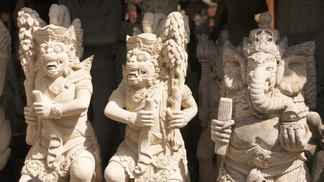 Tilt down, revealing a row of white stone statues for sale