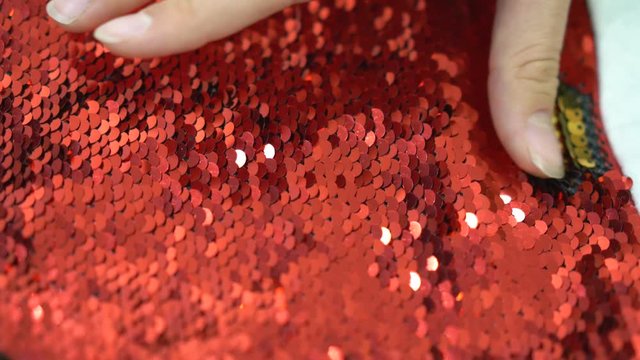 gold and red sequins for sewing in a hand on a white background