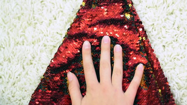 gold and red sequins for sewing in a hand on a white background